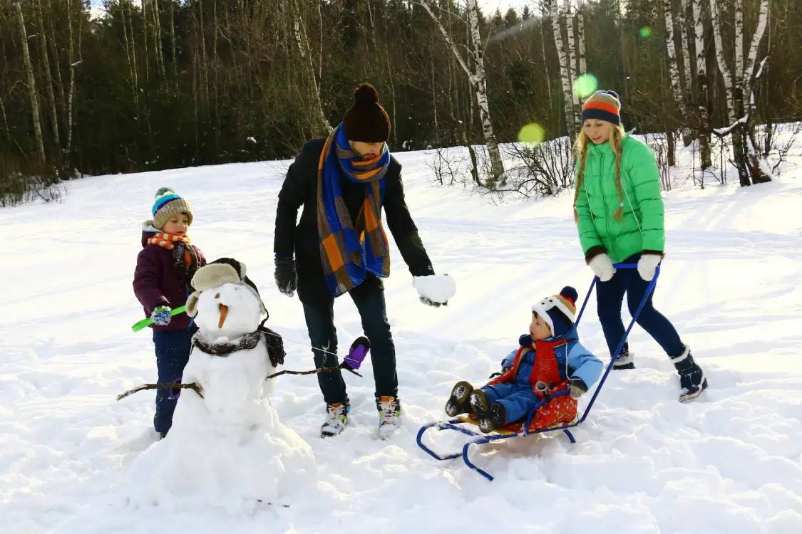 Family building a snowman and playing in the snow at Mt. Buller