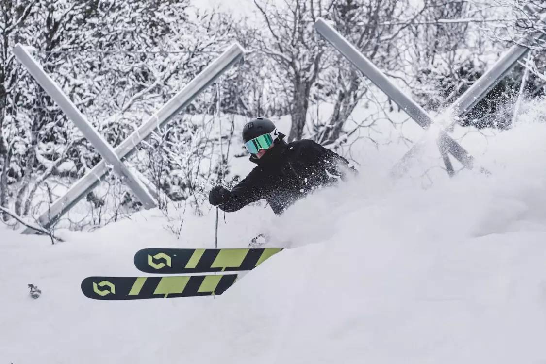 Snowboarder performing a trick against a snowy Mt. Buller backdrop.